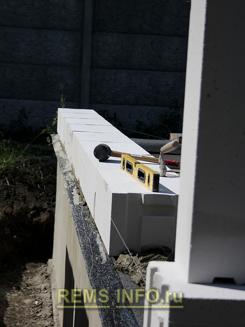 Корректировка ровности кладки стен из газоблока с помощью уровня.
