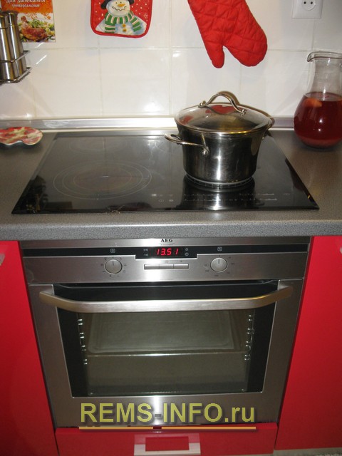 Варочная панель и духовка на кухне красного цвета.